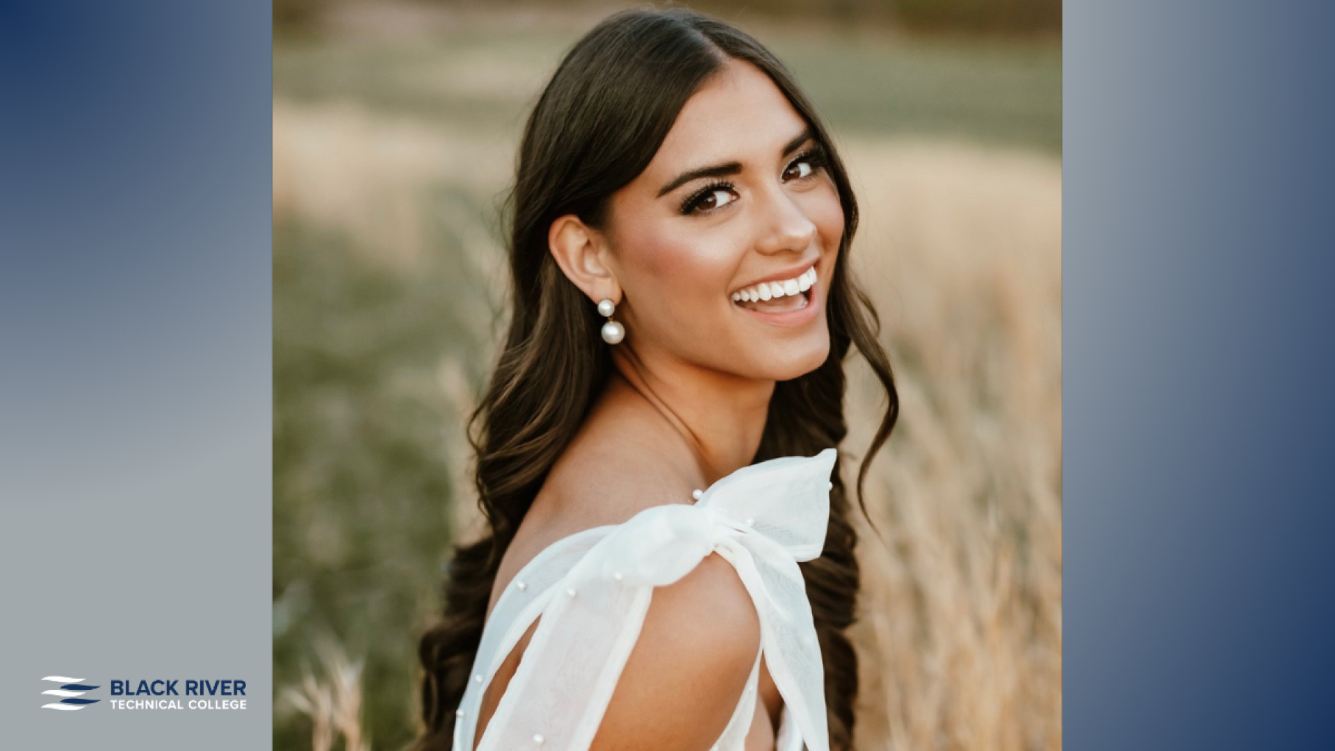 A young woman with long dark hair and pearl earrings, wearing a white off-shoulder top, smiles over her shoulder in a golden field, with Black River Technical College branding.